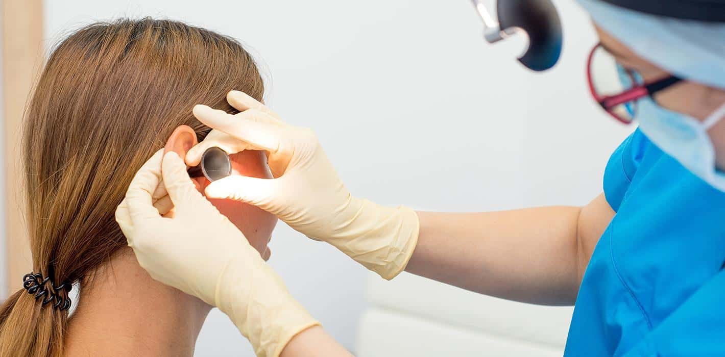 Dr. Kushnick examining a patient's ear with an otoscope